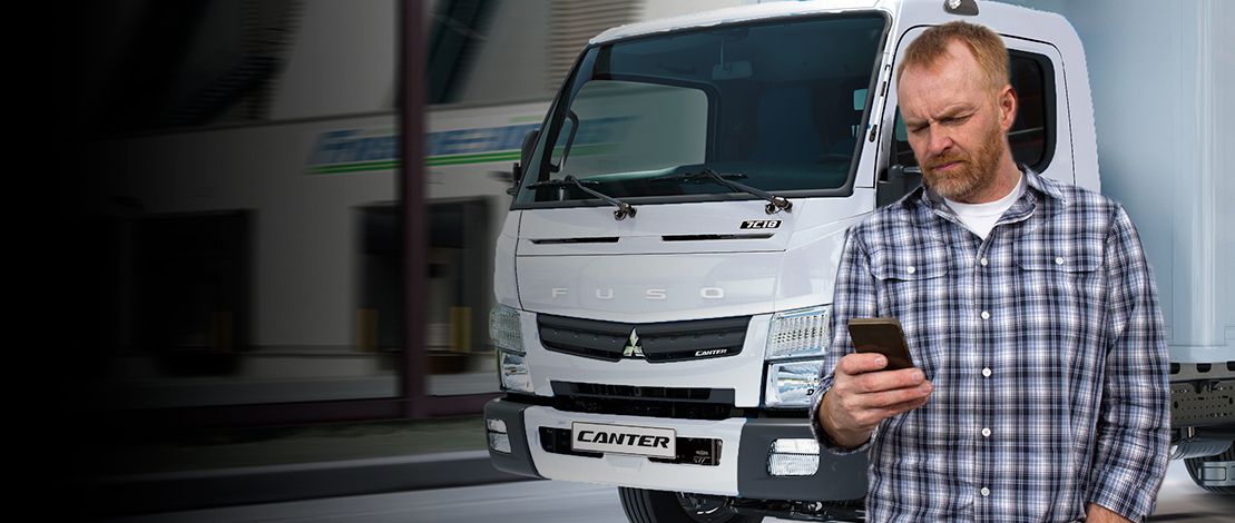 Hombre mirando el celular mientras pasa un camion fuso por detrás