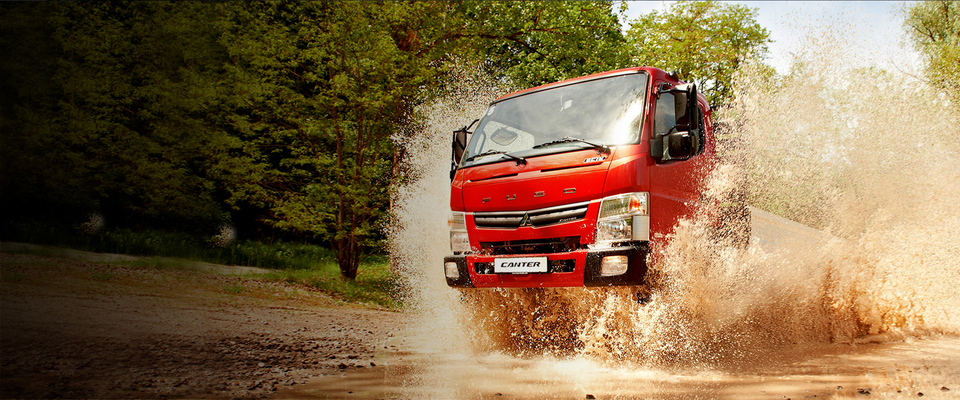 Camioneta Canter 615 4x4 Fuso Roja, cruzando un pequeño río con piedras salpicando agua