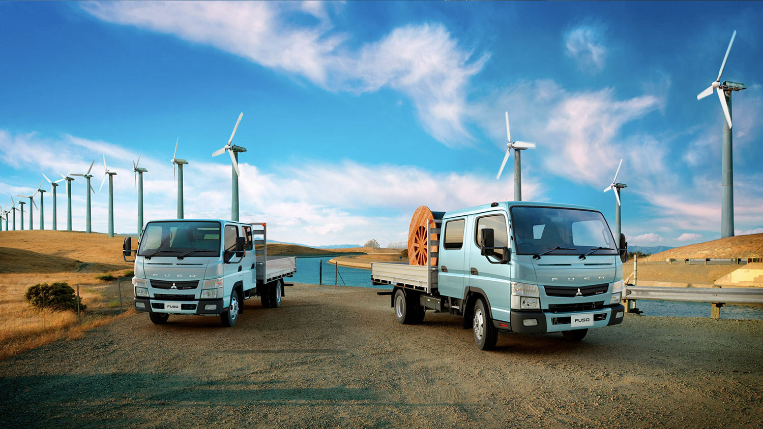 Camiones Canter 715 DC Celestes, cargando carretes industriales en un campo de energía eólica