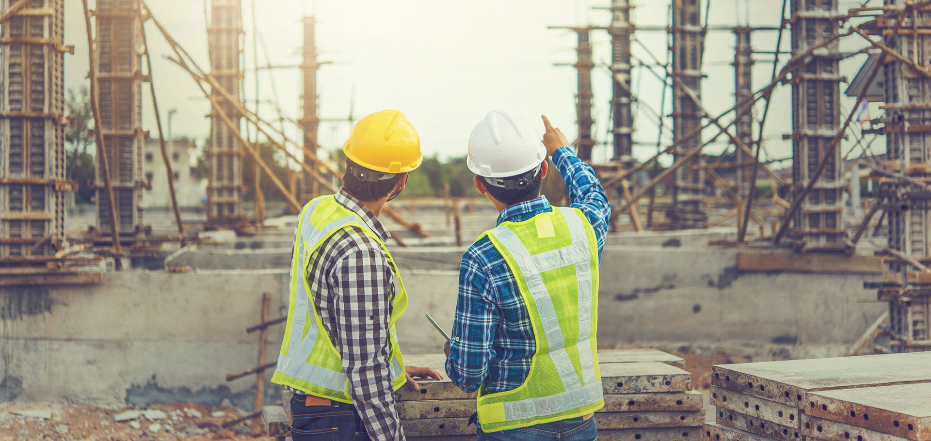 Ingenieros de construcción situados de espaldas, hablando sobre la edificación